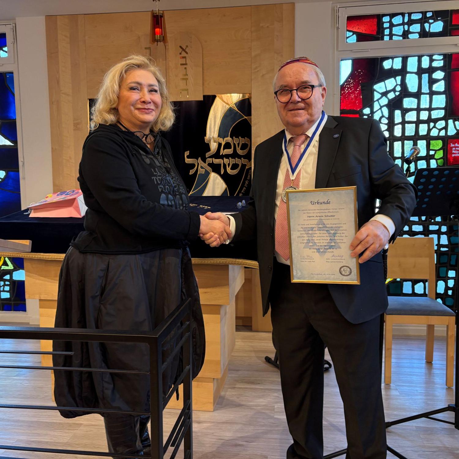 Leah Floh, Vorsitzende der jüdischen Gemeinde, zeichnet Armin Schuster, Vorsitzender der GCJZ, mit der Hans-Jonas-Medaille aus.